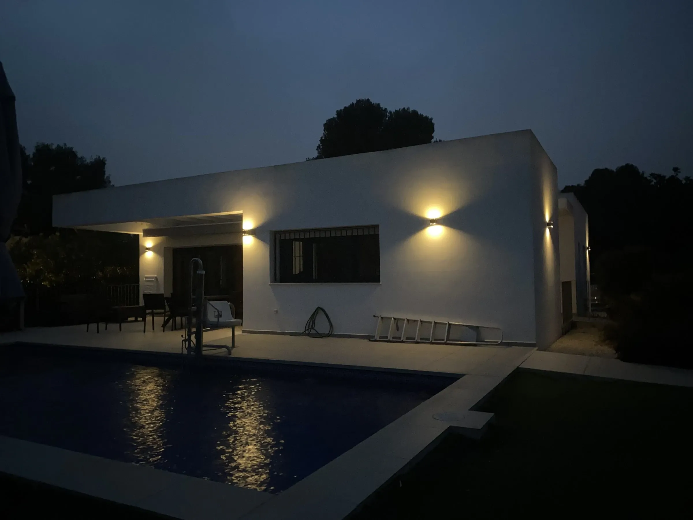 The villa lit up at night, reflected in the pool